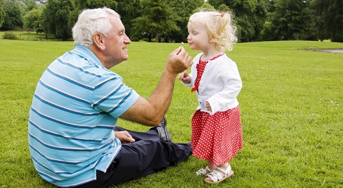 grandfather and granddaughter relax in park