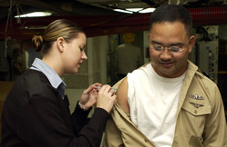 navy nurse giving a shot in the arm to active duty male