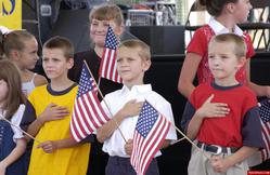 young children holding flags with hands over their heart