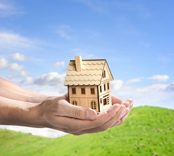 hands holding a wooden model house