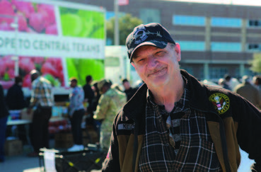 A smiling Veteran receiving food from one of the mobile pantries