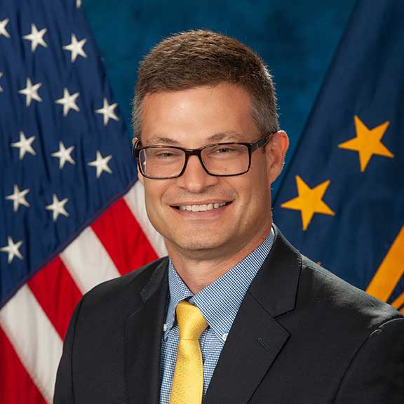 VA Executive Director of Suicide Prevention, Dr. Matthew Miller smiling in front of the American Flag.