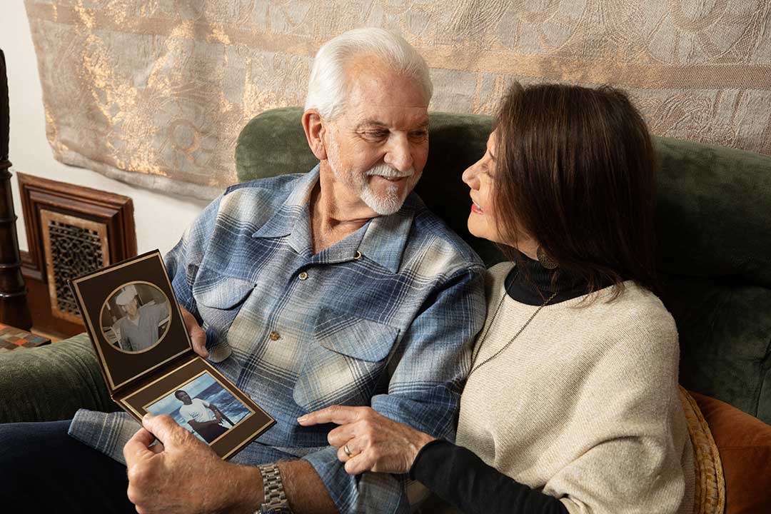 Joseph and Margaret looking at each other while holding a photo of Joseph during his service.