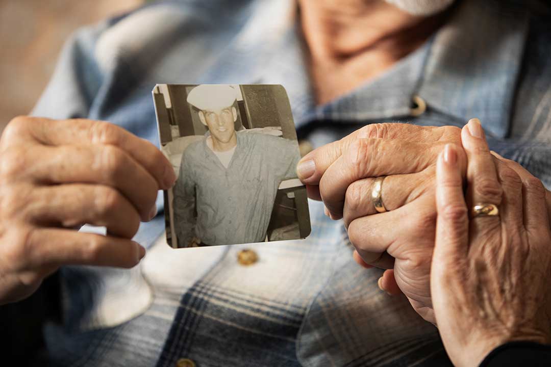 Close-up of Joseph and Margaret's hands holding a photo of Joseph during his service.