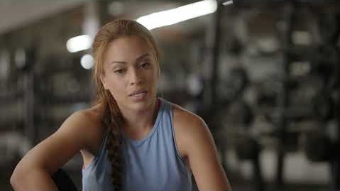 A women Veteran sitting in the gym as she looks slightly downward to the left as she is speaking.