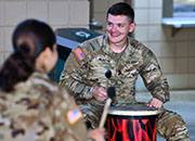 woman in front of photo display and Arkansas Army National Guard flag teaching soldiers