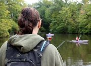 woman with back to camera fishing at lake and two others fishing in kayaks