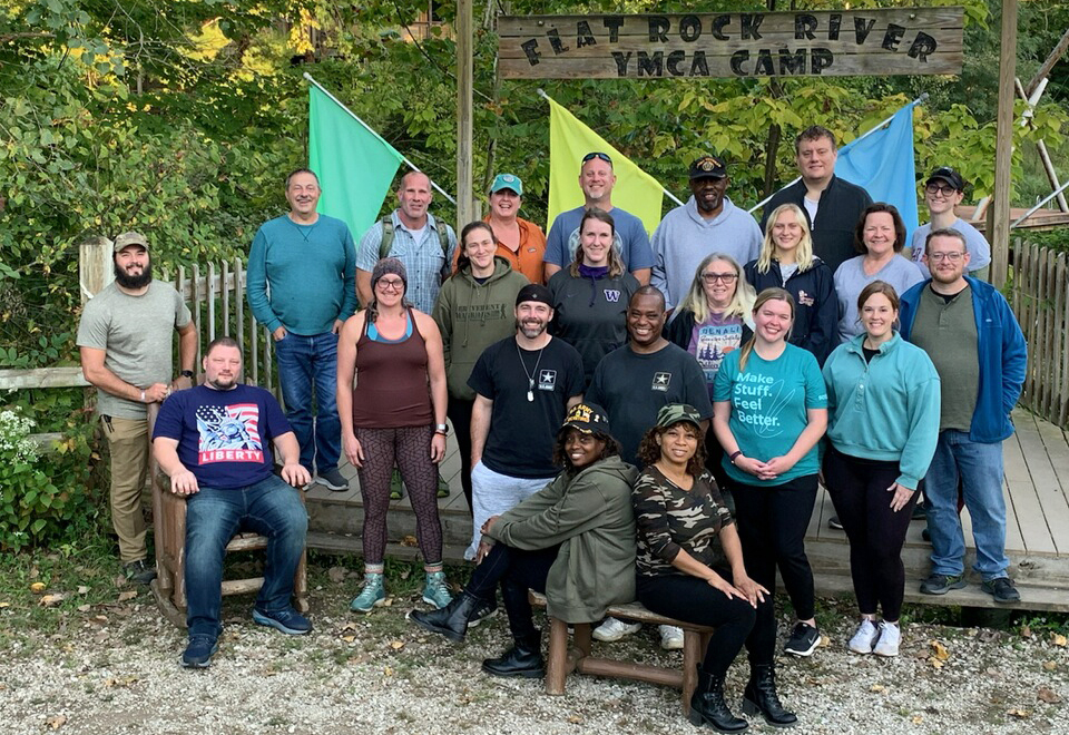 group of men and women at wooded camp with flags