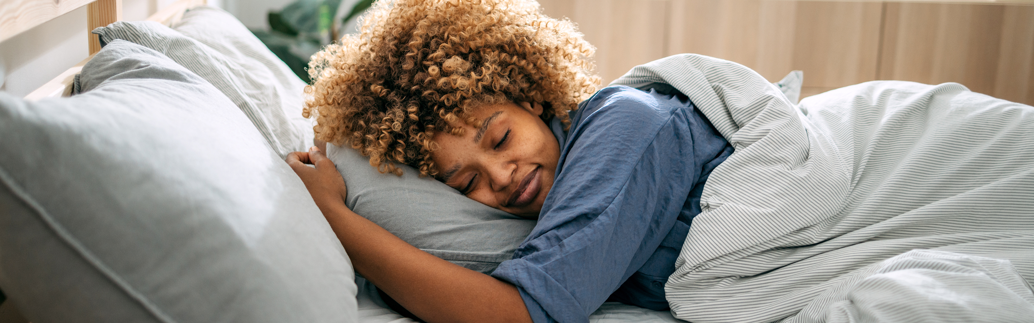 man sleeping while wrapped in blankets and wearing a sleep mask