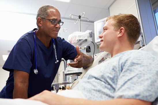 A clinician talking to a patient in a hospital bed.