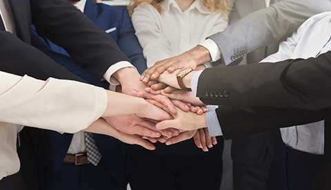 Diverse team of united coworkers standing with hands together